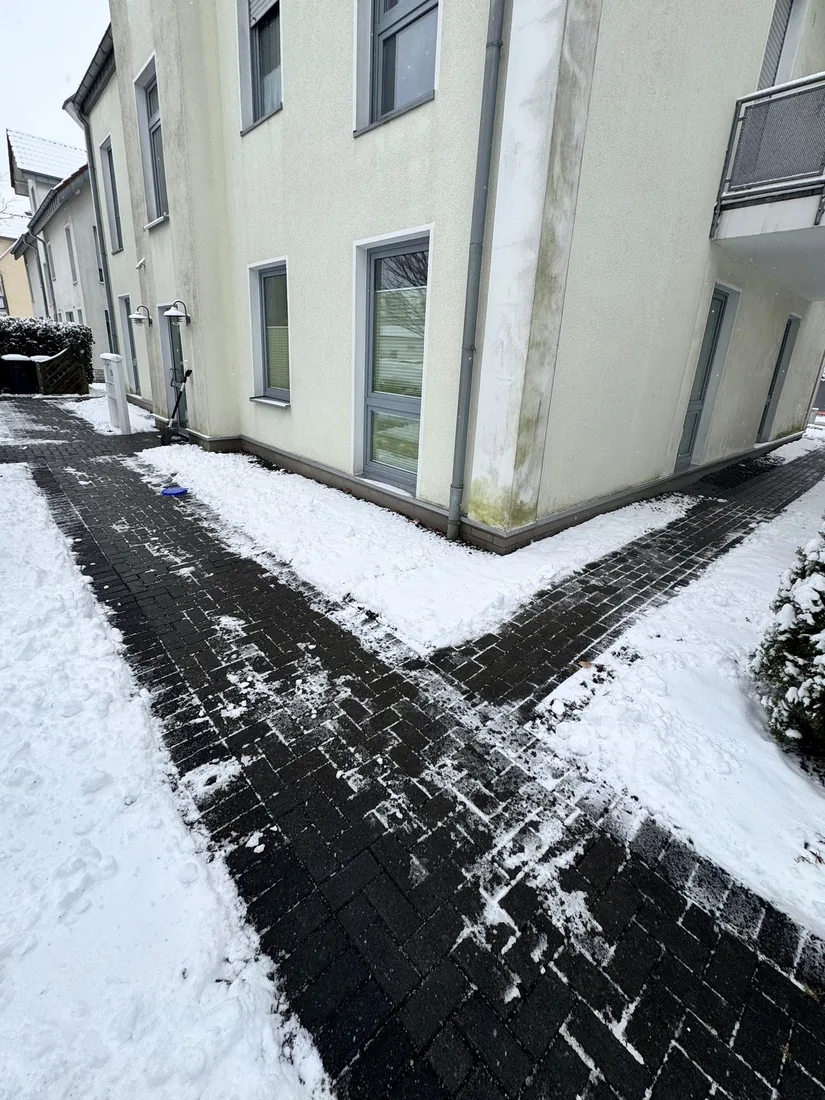 Geräumter Gehweg an einem Mehrfamilienhaus nach dem Schneefall